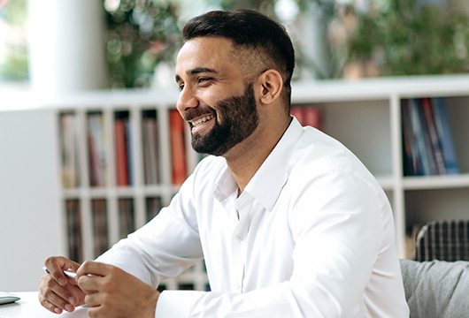 A smiling man sat down and holding a pen