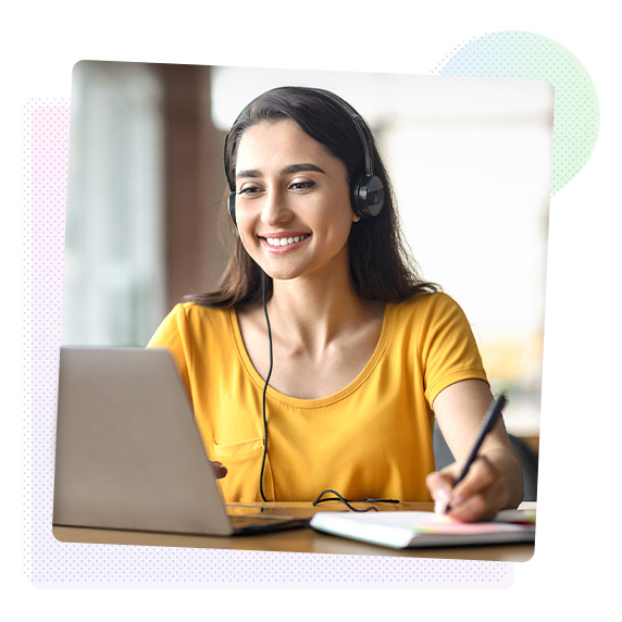 Smiling woman making notes in a notepad from a laptop screen