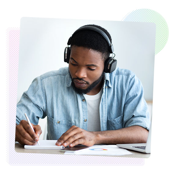 Man with headphones making notes in a notepad