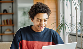 Man looking at a laptop and writing in a notebook